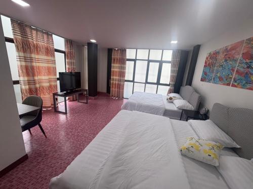 a hotel room with two beds and a flat screen tv at Destiny House Hostel in Hat Yai