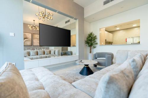 a living room with a couch and a flat screen tv at Nasma Luxury Stays - Opulent Family Escape in Marbella RAK in Ras al Khaimah