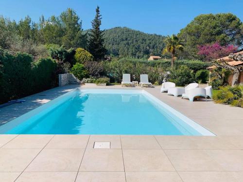 - une piscine dans une cour avec des chaises blanches dans l'établissement Le MOTU, à Cuers