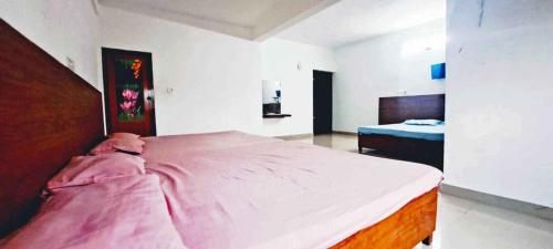 a bedroom with a large bed with a pink blanket at Elite Residency in Taliparamba