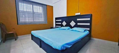 a bedroom with a bed with blue sheets and orange walls at Elite Residency in Taliparamba