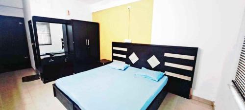 a bedroom with a large bed with blue pillows at Elite Residency in Taliparamba
