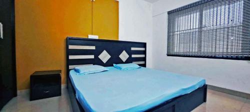 a bedroom with a bed with blue sheets and a window at Elite Residency in Taliparamba