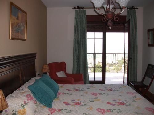 a bedroom with a bed and a chair and a window at Hotel Los Rebites in Huétor Vega