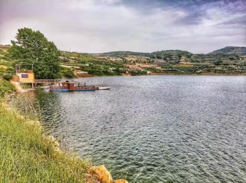 a lake with a boat in the middle of it at BiRKA - סוויטות מהממות מול נוף ברכת רם in Mas'ade