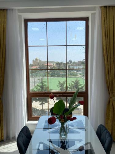 a table with a vase of flowers in front of a window at Style Home Buzovna in Baku