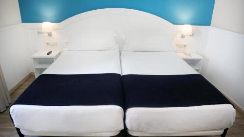 a large white bed in a room with two tables at 1881 Hotel Balneario Vichy Catalan in Caldes de Malavella