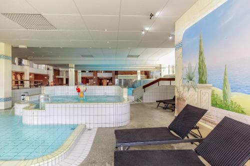 a large swimming pool with two chairs in a building at Englmar Apartments with free WELLNESS and FITNESS in Sankt Englmar