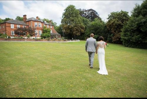 a bride and groom walking in a field at Brandshatch Place Hotel & Spa in Dartford