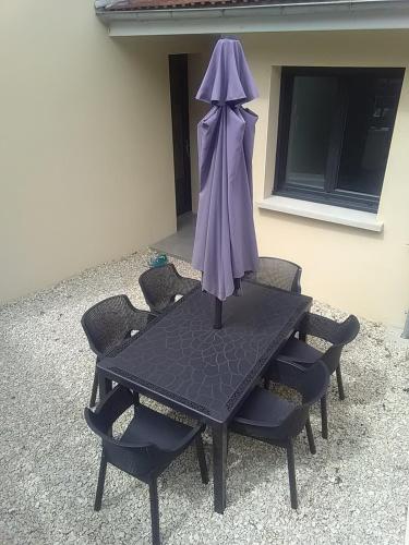 a table with chairs and an umbrella on it at Aux 3 épis in Dienville