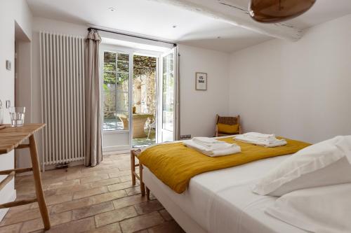 a bedroom with a bed and a table and a window at MAS MILLÉSIME - Chambre double - petit déjeuner - piscine - Mas du XVIIIème siècle proche Saint-Rémy-de-Provence in Mas blanc des Alpilles