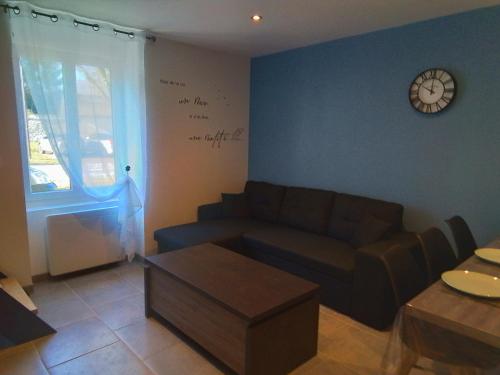 a living room with a couch and a clock on the wall at Aux 3 épis in Dienville