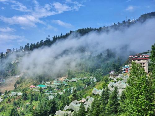 a village on a hill in the clouds at The Kufri House in Fagu