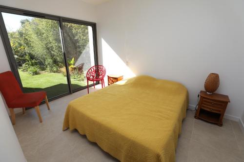 - une chambre avec un lit jaune et une grande fenêtre dans l'établissement Villa NAOUSSA vue mer proche plage, à Carqueiranne