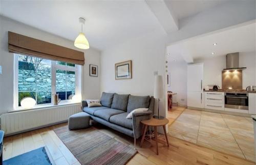 a living room with a blue couch and a kitchen at Cosy Ramelton Cottage in Ramelton