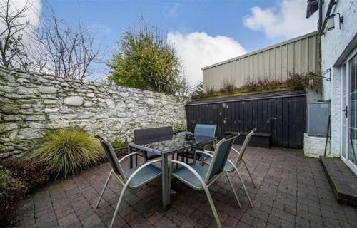 a patio with a table and chairs and a stone wall at Cosy Ramelton Cottage in Ramelton