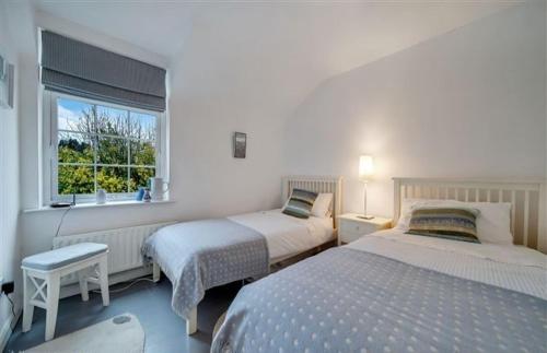 a white bedroom with two beds and a window at Cosy Ramelton Cottage in Ramelton