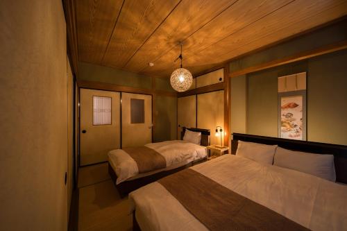 een slaapkamer met twee bedden en een hanglamp bij 別府温泉 小倉の湯 in Beppu