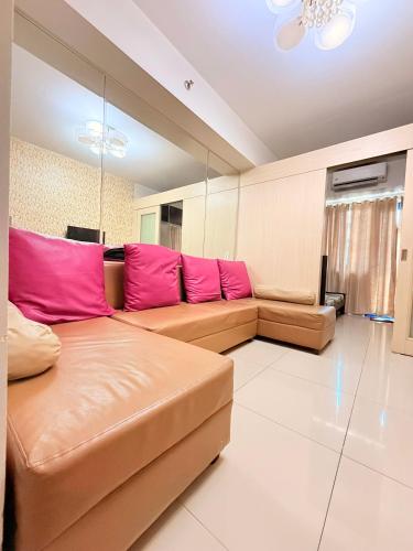 sala de estar con sofá marrón con almohadas rosas en Sea Residences MOA Manila by Paul, en Manila