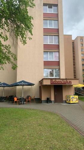 a building with tables and umbrellas in front of it at Butas Čiurlionio gatvėje in Pakopi