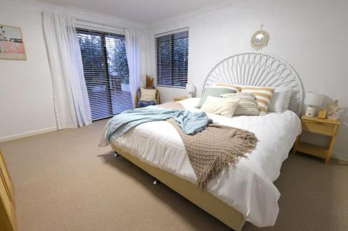 een slaapkamer met een groot wit bed en ramen bij Royal-Tee Retreat in Dunsborough
