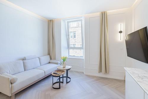 a white living room with a couch and a tv at Modern Apartament near city centre in Perth