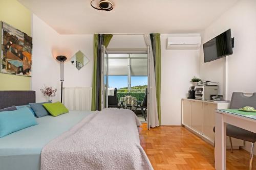 a bedroom with a bed and a desk and a kitchen at Jasna - apartman studio in Pula