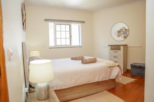 een witte slaapkamer met een bed en een spiegel bij Rosária Flat in Santa Cruz