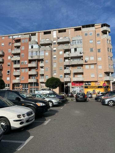 a parking lot with cars parked in front of a large building at Loznica Centar Apartman in Loznica