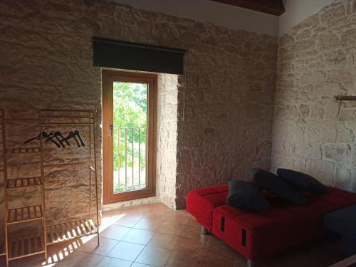 a living room with a red couch and a window at Casa Rurale Pietra Bianca in Roccamorice