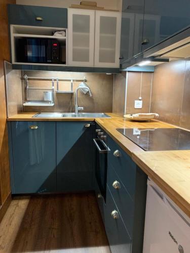 a kitchen with blue cabinets and a sink at Studio charmant et confortable Brides Les Bains in Brides-les-Bains