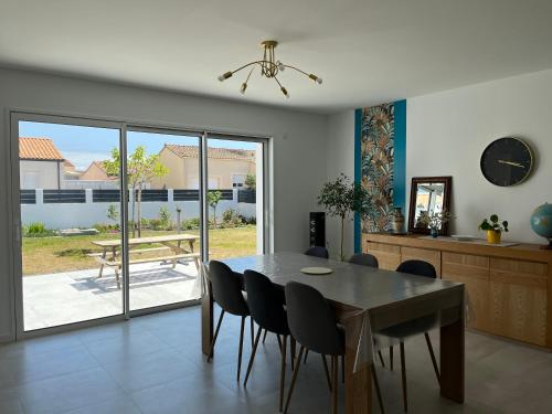 une salle à manger avec une table et des chaises ainsi qu'une terrasse dans l'établissement Maison neuve spacieuse - 6 pers - proche St Gilles, à Givrand
