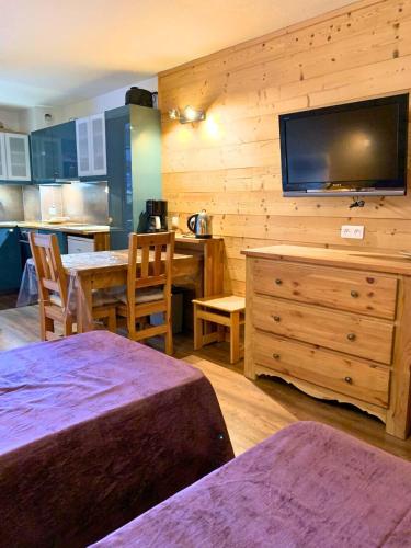 a room with a table and a tv on a wall at Studio charmant et confortable Brides Les Bains in Brides-les-Bains