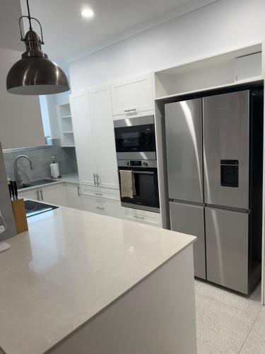 a white kitchen with a stainless steel refrigerator at Soldiers Point Escape in Soldiers Point