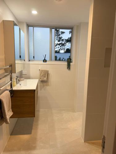 a bathroom with a sink and a shower with a window at Soldiers Point Escape in Soldiers Point
