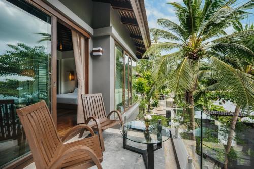 a balcony with two chairs and a glass table at The Kala in Amphoe Koh Samui