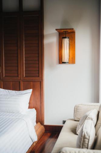 a bedroom with a bed and a couch and a light at The Kala in Amphoe Koh Samui