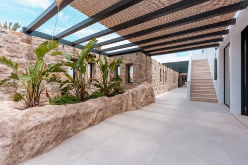 a patio with a stone wall and a wooden ceiling at Noir Mykonos in Mýkonos City