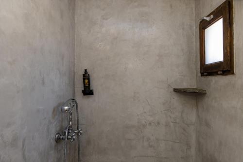 a shower in a bathroom with a soap dispenser on the wall at Κυκλαδίτικο Studio in Kionia