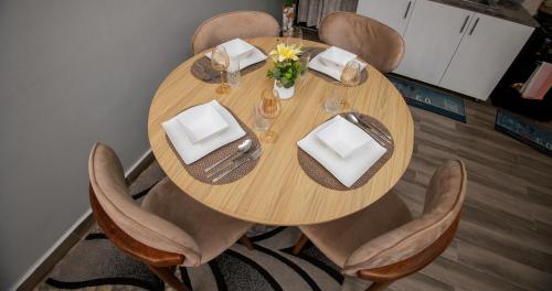 a wooden table with chairs and a table with plates and napkins at Luxury 2BR Apartment with AC, Wi Fi, Backup Power Ideal for Families , Bukoto in Kampala