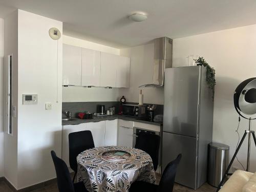 une cuisine avec une table et un réfrigérateur en acier inoxydable dans l'établissement Superbe t2 route de ville Bastia, à Bastia