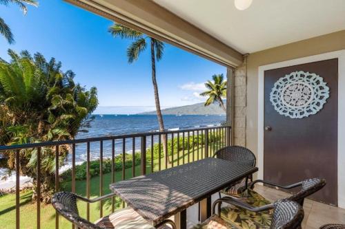 a balcony with a table and chairs and the ocean at KIHEI BEACH, #210 condo in Kihei