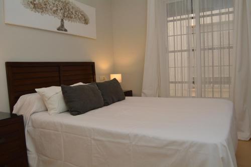 Un dormitorio con una cama blanca grande y una ventana en Apartamento La Rosa, en El Puerto de Santa María