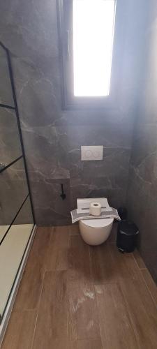 a small bathroom with a toilet and a window at Loft bianco nero in Tríkala