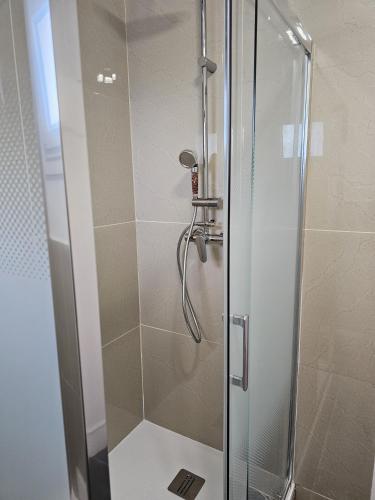 une douche dans une salle de bain avec une porte vitrée dans l'établissement Élégant 3 pièces proche Paris La Défense, à Bezons