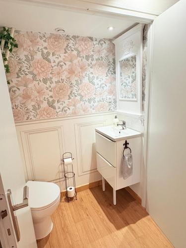 a bathroom with a toilet and floral wallpaper at Le Manoir 1977 in Jaunay-Marigny