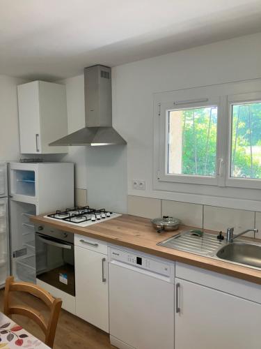 une cuisine avec des armoires blanches et un comptoir en bois dans l'établissement Gîte Espinasse, à Soustons