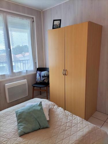 - une chambre avec un lit, une armoire et une fenêtre dans l'établissement Paisible appartement à deux pas de la Plage, à Saint-Hilaire-de-Riez