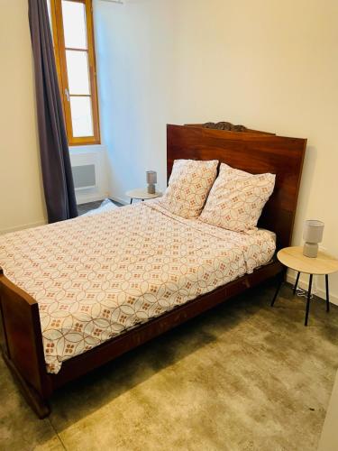 - une chambre avec un lit doté d'une tête de lit en bois et d'une table dans l'établissement Auprès du Rhône, à Saint-Vallier