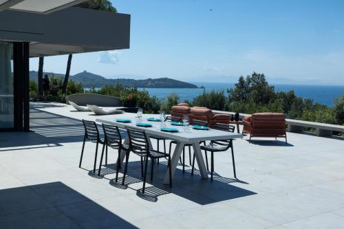 a table and chairs on a patio with a view of the ocean at Extreme Luxury Villa in Punta Ala with Private Pool, SPA and Gym in Punta Ala